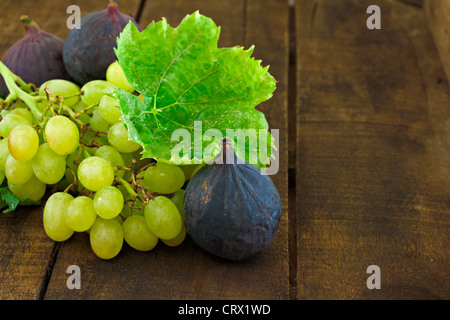 Fichi e uva sul vecchio tavolo in legno Foto Stock