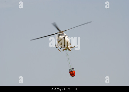 Vigile del fuoco elicottero in volo portante una benna extinguising Foto Stock