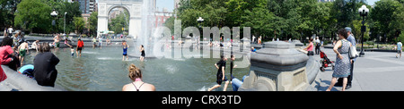 I Newyorkesi e visitatori gravitano verso i parchi con fontane come la fontana di Washington Square Park, per raffreddarsi Foto Stock