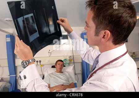 Un medico sul suo ospedale round esamina un paziente di raggi x. Foto Stock