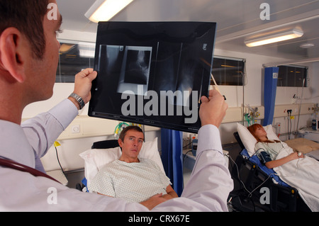 Un medico sul suo ospedale round esamina un paziente di raggi x. Foto Stock
