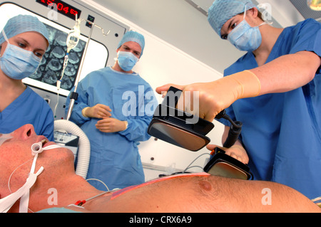 I medici utilizzando un defibrillatore per rianimare un maschio di attacco di cuore vittima. Foto Stock