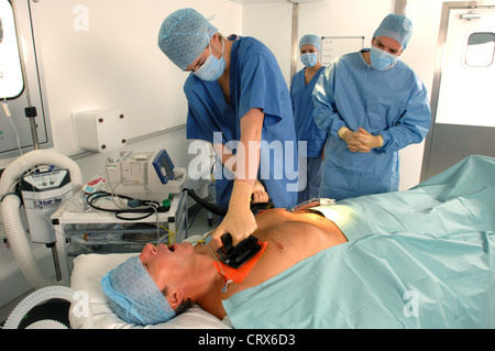 I medici utilizzando un defibrillatore per rianimare un maschio di attacco di cuore vittima. Foto Stock