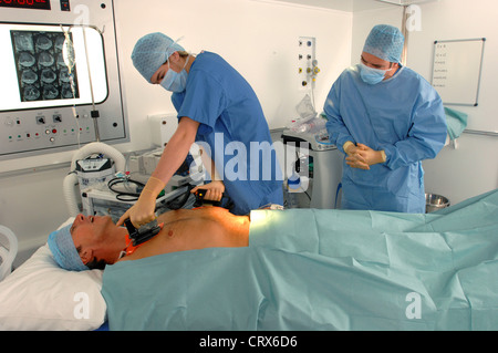 I medici utilizzando un defibrillatore per rianimare un maschio di attacco di cuore vittima. Foto Stock