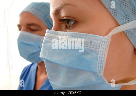 Close up di un medico di sesso maschile e di sesso femminile che indossa infermiere blu tappi chirurgico, maschere e abiti. Foto Stock