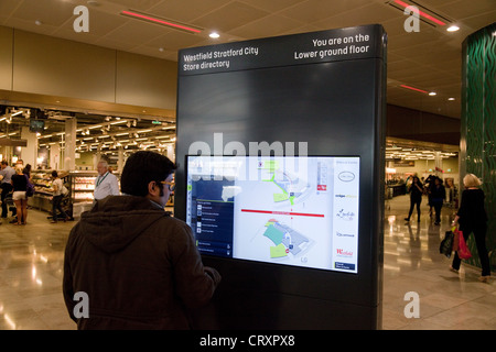 Un uomo la lettura della directory del negozio mappa al centro commerciale Westfield Mall, Stratford London REGNO UNITO Foto Stock