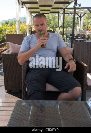 Uomo greco rilassarsi e bere un frappé Foto Stock