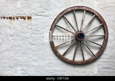 Rustico ruota di carro appeso a una parete Foto Stock