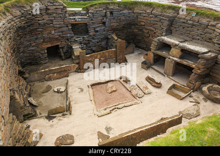Gli scavi della dimora primordiale e mobili di pietra nella preistoria villaggio neolitico a Skara Brae nelle Isole Orcadi Scozia UK Foto Stock