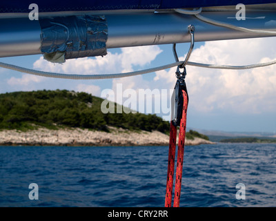 Barca a vela boom con raccordi in mare nei pressi di isola in dietro Foto Stock