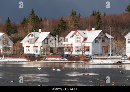 Le case e gli edifici confinanti con lo stagno, Reykjavik, Islanda, sotto una tempesta cielo grigio Foto Stock