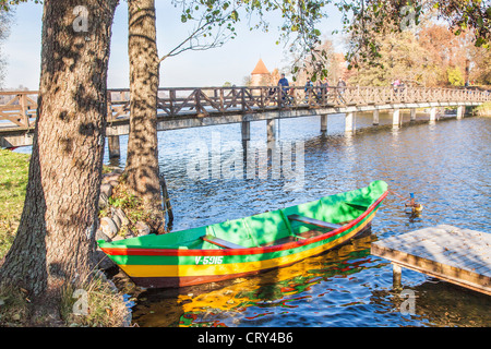 Un colorato le barche a remi ormeggiate sul Lago di Galve, Trakai, Lituania tramite una passerella in legno che conduce al Castello di Trakai Foto Stock