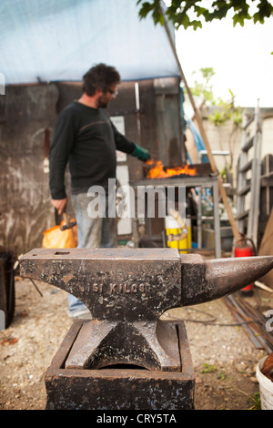 Fabbro decorativo facendo lavorare il ferro mediante un martello e l'incudine Foto Stock