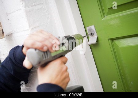 Fabbro la foratura della canna fuori yale serratura sul verde lime porta Foto Stock