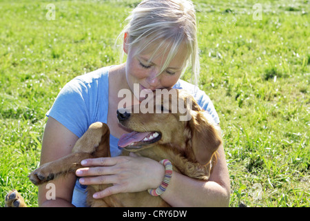 Giovane donna coccole un giovane Golden Retriever Canis lupus familiaris Foto Stock