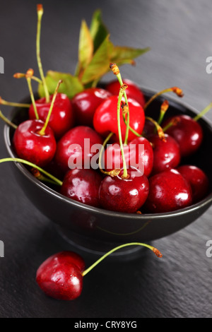 Le ciliege fresche in un recipiente su sfondo nero Foto Stock