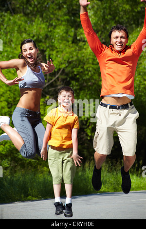 Tiro dinamico di una famiglia di sportivi jumping all'aperto Foto Stock