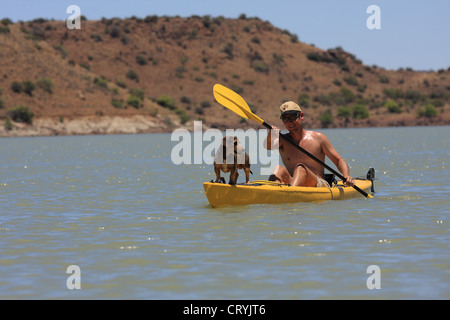 Giovane uomo kayak con un cane sulla parte anteriore del kayak Foto Stock