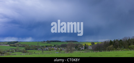 Nuvole temporalesche nella formazione delle nuvole sopra il villaggio Asthall in primavera in Cotswolds, Oxfordshire, Regno Unito Foto Stock