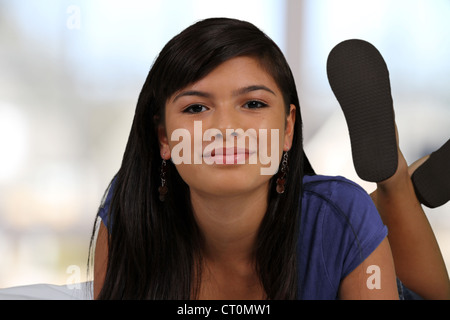 Ragazza adolescente che stabilisce nel suo letto nella sua casa Foto Stock