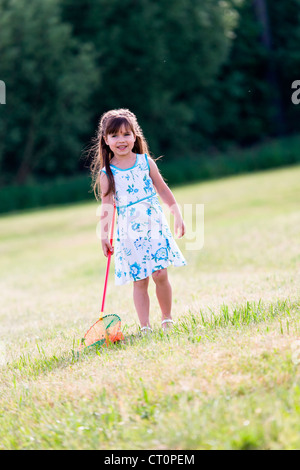 Ragazza che gioca con butterfly net in giardino Foto Stock