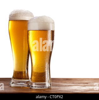 Due bicchieri di birra su di un tavolo di legno. Isolato su uno sfondo bianco. Foto Stock