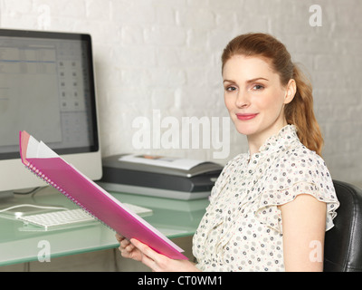 Imprenditrice con cartella nella scrivania Foto Stock