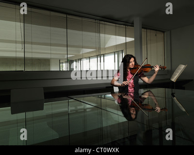 Donna suona il violino in ufficio business Foto Stock