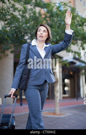 Imprenditrice salutando taxi sulla strada Foto Stock