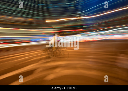 Panoramiche, slow-esposizione fotografia di un ciclista e le luci al neon di Manhattan a New York di notte. Foto Stock