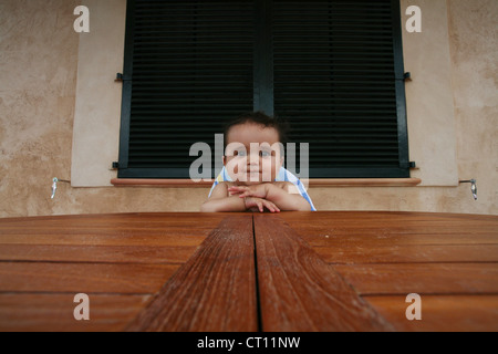 Bambino seduto nella sedia alta a tavola Foto Stock