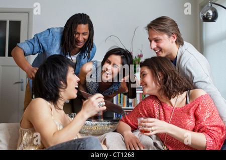Gli amici di ridere insieme in salotto Foto Stock