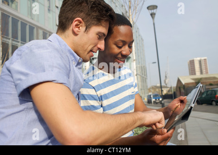 Gli uomini utilizzano computer tavoletta su strada Foto Stock