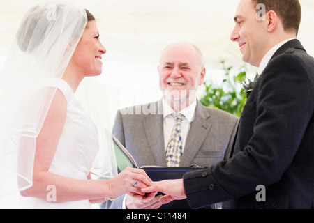 Sposa mettendo anello sul dito sposi Foto Stock