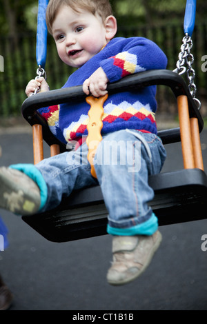 Ragazzo giocando in swing sul parco giochi Foto Stock