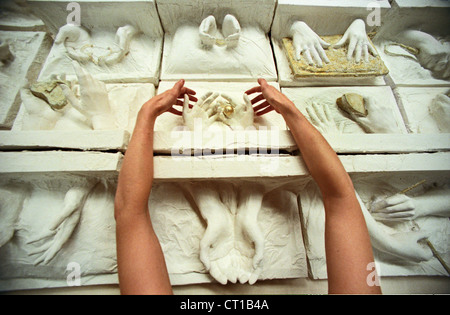 Una donna artista disponendo di calchi di mani femminili che simboleggia il lavoro delle donne nel mondo vale il suo peso in oro Foto Stock