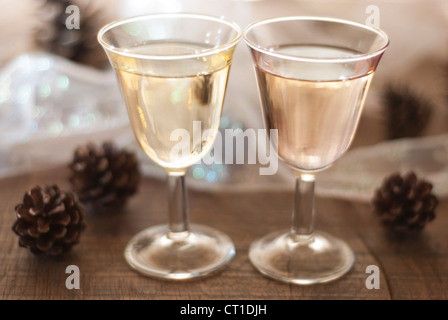 Due celebrativo pieno bicchieri da vino in un incandescente scena da tavolo con decorazioni di Natale. Foto Stock