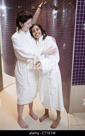 Le donne in accappatoi abbracciando nella doccia Foto Stock
