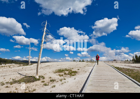 Donna in giacca rossa che porta uno zaino camminando sul Boardwalk Upper Geyser Basin Parco Nazionale di Yellowstone Foto Stock