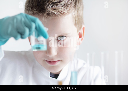 Studente di esaminare il liquido nel bicchiere Foto Stock