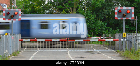 I binari ferroviari rosso lampeggiante spia livello di segno attraversando i cancelli di barriera stradale del paese treni passeggeri motion blur a Margaretting Essex England Regno Unito Foto Stock