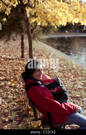 Madre con suo Figlio seduto sul banco di fronte a un lago Foto Stock