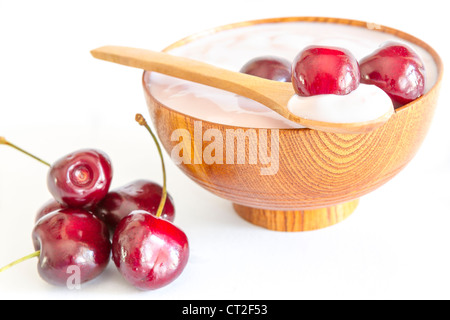 Le ciliege fresche di frutta con yogurt in una ciotola di legno e cucchiaio Foto Stock