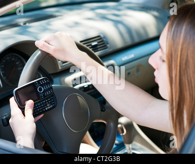 Ragazza adolescente sms sul cellulare durante la guida Foto Stock