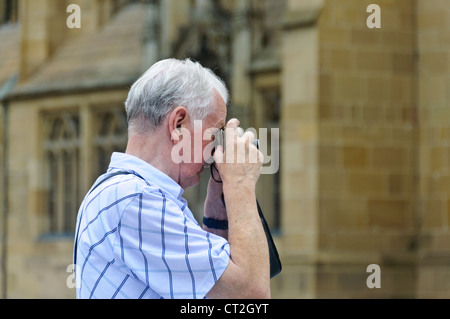 Senior Citizen fotografo con il grigio capelli bianchi prende le immagini con punto e sparare fotocamera compatta San Kilan Chiesa di Heilbronn Foto Stock