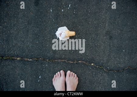 Piedi con i caduti cono gelato sul marciapiede. Foto Stock