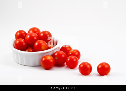 Rossi pomodori ciliegini in ciotola bianco su sfondo bianco Foto Stock