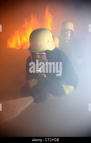 I vigili del fuoco, il fuoco agli uomini, scontri a fuoco la formazione a un incendio nella casa di formazione. I vigili del fuoco con apparecchi di respirazione. Foto Stock