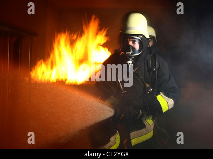 I vigili del fuoco, il fuoco agli uomini, scontri a fuoco la formazione a un incendio nella casa di formazione. I vigili del fuoco con apparecchi di respirazione. Foto Stock