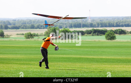 L uomo si lancia in cielo RC glider, sul campo in erba Foto Stock